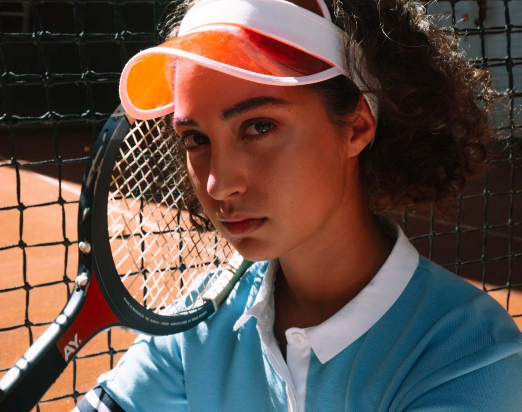 Femme avec une tenue de sport et une raquette de tennis sur un court.